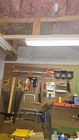 Wide view of hand tools on pegboard including saws, clamps, vises, T-square, and heat gun