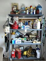 Full view of metal shelving unit holding assorted home, automotive, and yard maintenance supplies including fluids, chemicals, and tools.