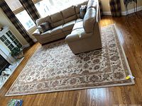 Full view of floral oriental rug under sectional sofa, showing overall size and pattern.