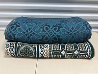Photo of two folded vintage blankets, blue one on top with intricate pattern and green one underneath