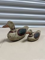 Two wooden duck decoys, one large and one small, showing side view and front angle with painted details