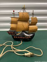 Front view of the Leviton Flying Dutchman ship lamp showing sails, hull with red cannon port details, power cord and plug.