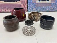 Overview of all ceramic pots, flower frog pin holders, and metal frog figurines included in the lot.