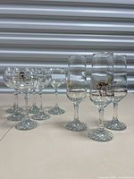Clear glassware set of 3 champagne glasses with gold trim and 6 wine glasses arranged in two rows, showing overall lot composition.
