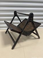 Folded painted bamboo style magazine rack angled view showing woven panels and wooden frame painted dark brown.