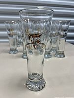 Single pilsner glass showing clear glass, textured base, and 22kt gold Olympic Flame design.
