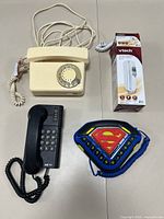 Lot of four phones including beige rotary dial, black push-button, Superman-themed push-button, and boxed VTech handset