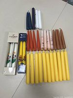 Photo showing all candles arranged on a surface including boxed and loose candles of multiple colors.