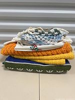 Stack of assorted linens and doilies showing folded crocheted and textured fabrics in multiple colors including white, blue, yellow, and green.