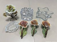 Photo of 3 porcelain rose flower wall hangings and 3 clear glass dishes including flower-shaped, star-shaped, and compartmented container.