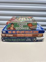 Stack of four vintage board game boxes showing titles and approximate condition from sides: Wheel of Fortune (Tyco 1992), The Six Million Dollar Man (Parker 1975), Bionic Crisis (Parker 1975), and Are You Afraid of the Dark (Nickelodeon 1995).
