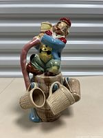 Front and full view of the ceramic decanter depicting a drunken clown on a barrel with three ceramic mugs attached