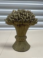 Full frontal view of an antiqued brass tone cast iron door stop shaped as a sheaf of wheat, showing the entire design and structure.
