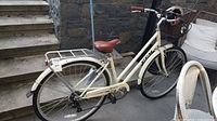 Full side view of cream CCM Munich step-through bicycle showing frame, basket, rack