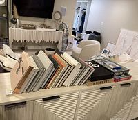 Stack of coffee table books arranged on a textured console table in living room setting