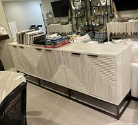 Full front and side view of light wood sideboard with four textured doors and black metal base