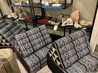 Two triangular floor cushions with black and white tribal print on the floor against shelving with minerals