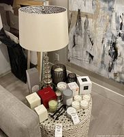 Overall view of silver table lamp, various candles and candle accessories on round table