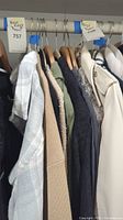 Photo of various women's jackets hanging on a rack including light plaid, beige knit, olive green blazer, black long blazer and grey knit sweater jacket.