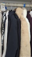 Six jackets on a rack: zebra‐style patterned, white lightweight, black blazer, tan faux shearling, off‐white faux shearling, plum wool coat