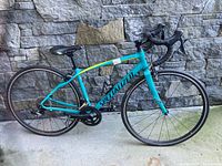 Full side view of bicycle leaning against stone wall