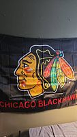 Full view of the Chicago Blackhawks flag showing the logo and text on black fabric.