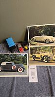 Four die-cast toy vehicles and three classic car photo prints arranged on a surface.