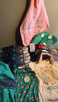 Photo showing pink Pink Floyd dog hoodie, green elf hats, several black SixBones dog leashes, green Merry & Bright dog T-shirt, Woodstock T-shirt, Bark & Co dog hat.