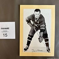 Front side of vintage 1946-64 Group 2 Beehive hockey photograph featuring player Tom Johnson in Montreal uniform, attached to Manila backing with a strip of glue at top.