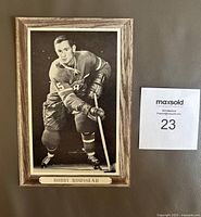 Front view of framed Bobby Rousseau hockey photo showing player in action, mounted on wood-look frame with nameplate.