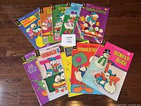 Lot of 10 Gold Key Donald Duck comic books fanned out on a wooden floor, showing colorful covers with various editions from 1975-1979.