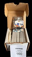 Open cardboard box filled with a large set of football cards with a visible Troy Aikman card on top.
