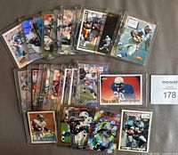 First photo of 25 Barry Sanders football cards laid out on a flat surface showing front side of the cards with a MaxSold lot number card visible.