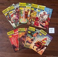 All nine Classics Illustrated comic books laid out on dark wood floor showing front covers.