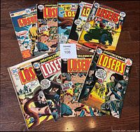 Top view of all 9 DC The Losers comic books laid out, showing colorful vintage comic covers and issue numbers.