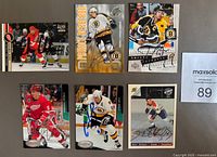 Front view of 6 autographed hockey cards including Patrice Bergeron, Cam Neely, Henri Richard, Bobbie Clarke, and others.