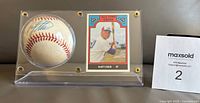 Full view of the signed baseball and Rusty Staub All Time Expos card in Lucite stand with MaxSold bidding number