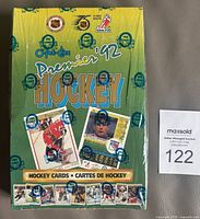 Front and top view of sealed 1991-92 OPC Premier hockey card wax box, showing green/yellow box with OPC wax seals all around and hockey card images.