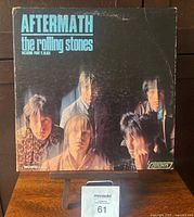 Front cover of The Rolling Stones "Aftermath" album showing band members with some crease and wear damage.