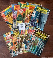 10 vintage D.C. The Unknown Soldier comic books arranged fan-wise showing front covers with varied war-themed illustrations and visible signs of age wear.