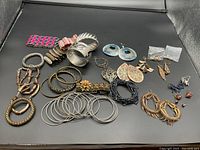 Full view of assorted bracelets and earrings including floral bracelet and colorful large dangle earrings