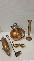 Photo of brass dolphin figurine, brass swans, copper pot with wrapped handle, and brass candle snuffer