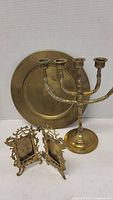 Photo showing all items: brass candelabra, two small ornate brass picture frames, and brass tray