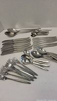 Full set of WMF stainless steel flatware arranged on surface, showing knives, forks, spoons of various sizes.