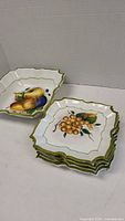 Stack of 6 square ceramic side plates and one bowl with fruit motifs, scalloped edges, green trim