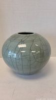 Front view of a round light green ceramic vase with crackle glaze pattern.