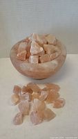 View of Himalayan salt bowl filled with salt chunks with some salt chunks placed in front.