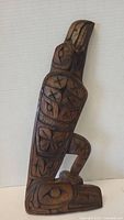 Front view of the carved raven figure showing detailed traditional indigenous carvings.