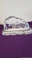 Crystal sculpture with an etched moose and foliage scene, set on a purple cloth background.