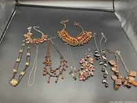 Overview photo showing all necklaces spread out on dark background, various styles and sizes visible.